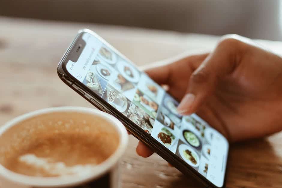 A hand holding a smartphone and a cup of coffee.