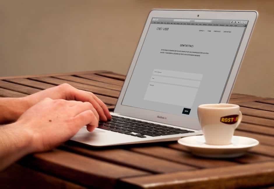 A person typing on a laptop on a wooden table.