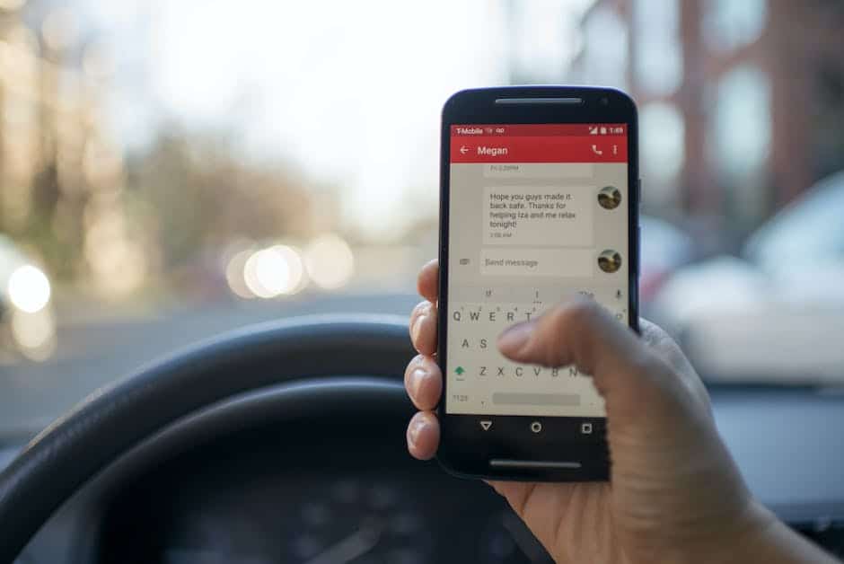 A person holding a cell phone while driving a car.