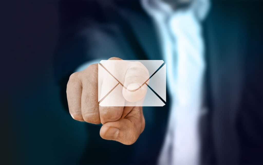A businessman's hand is pointing at an email envelope.