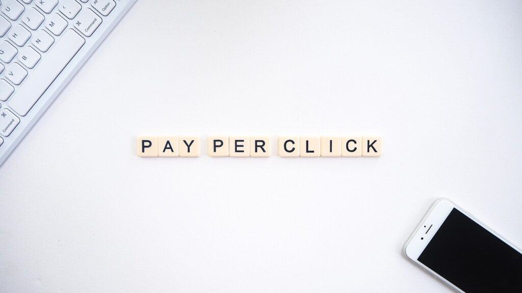 The word pay per click on a desk next to a phone and keyboard.