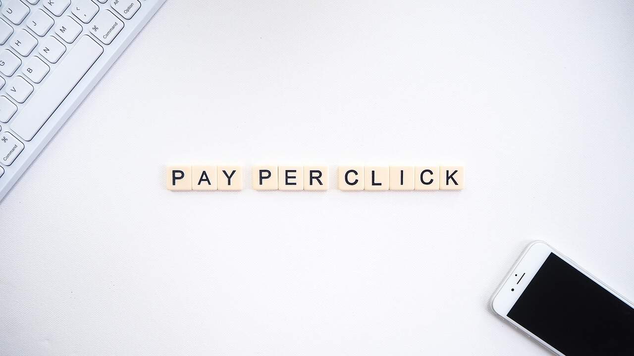 The word pay per click on a desk next to a phone and keyboard.