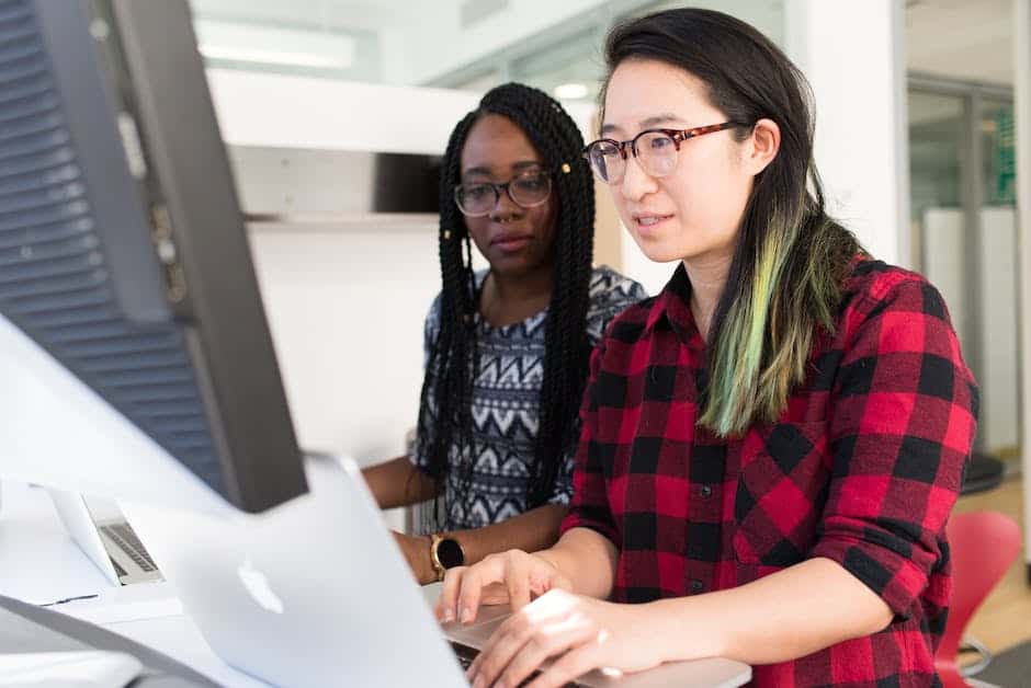 Two women working on a computer in an office.