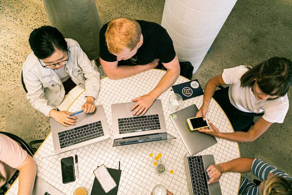 A group of people sitting around a table using laptops.