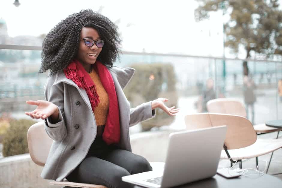 A black woman sitting on a bench with her laptop.