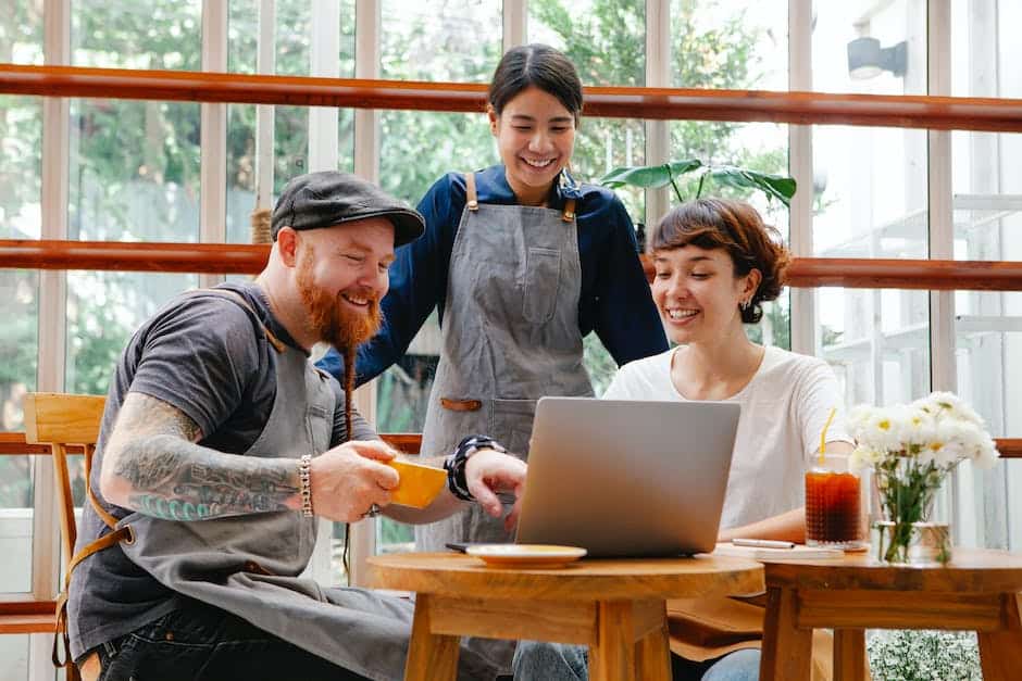 A group of people sitting at a table and using a laptop.