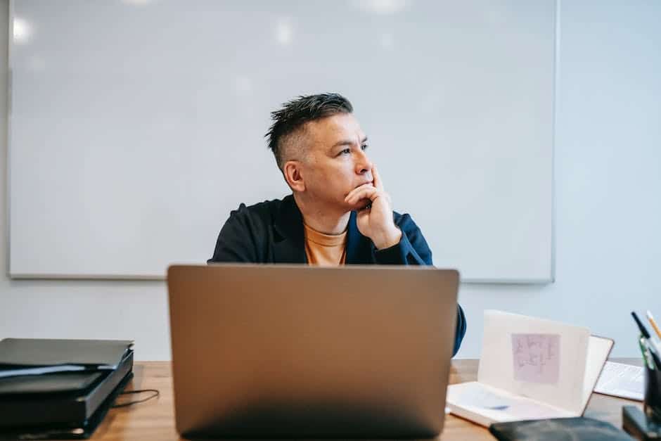 A man sitting at a desk with a laptop in front of him.