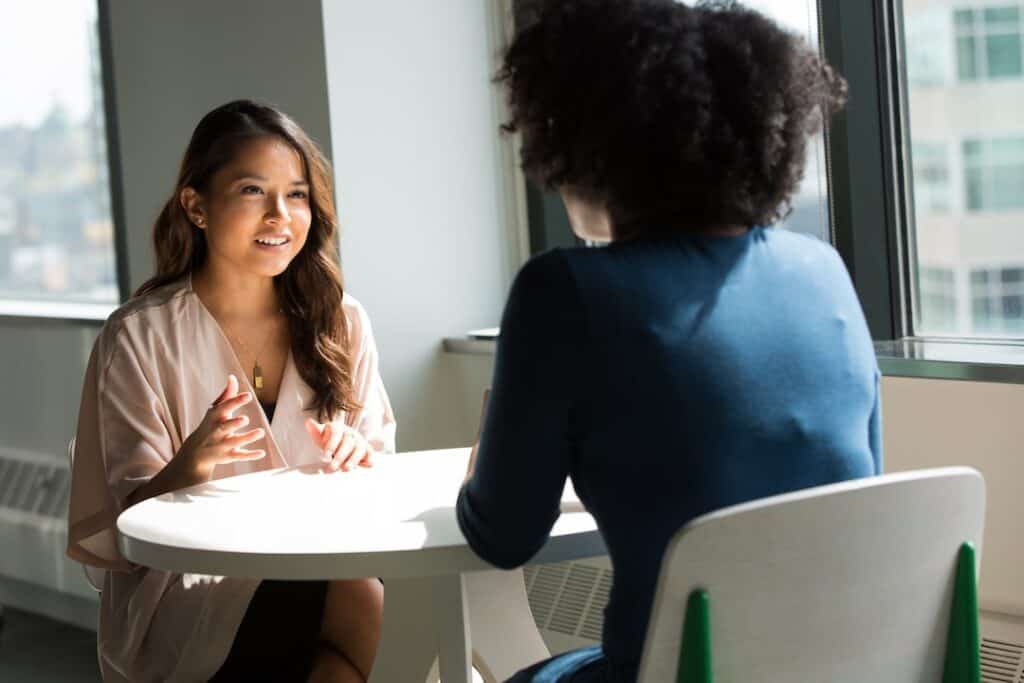 Two women talking at a table in an office.