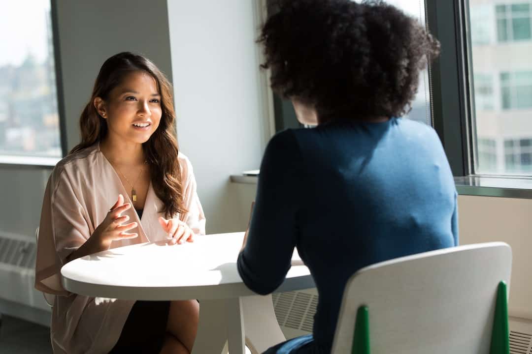 Two women talking at a table in an office.