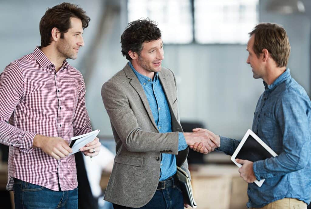 Three businessmen shaking hands in an office.