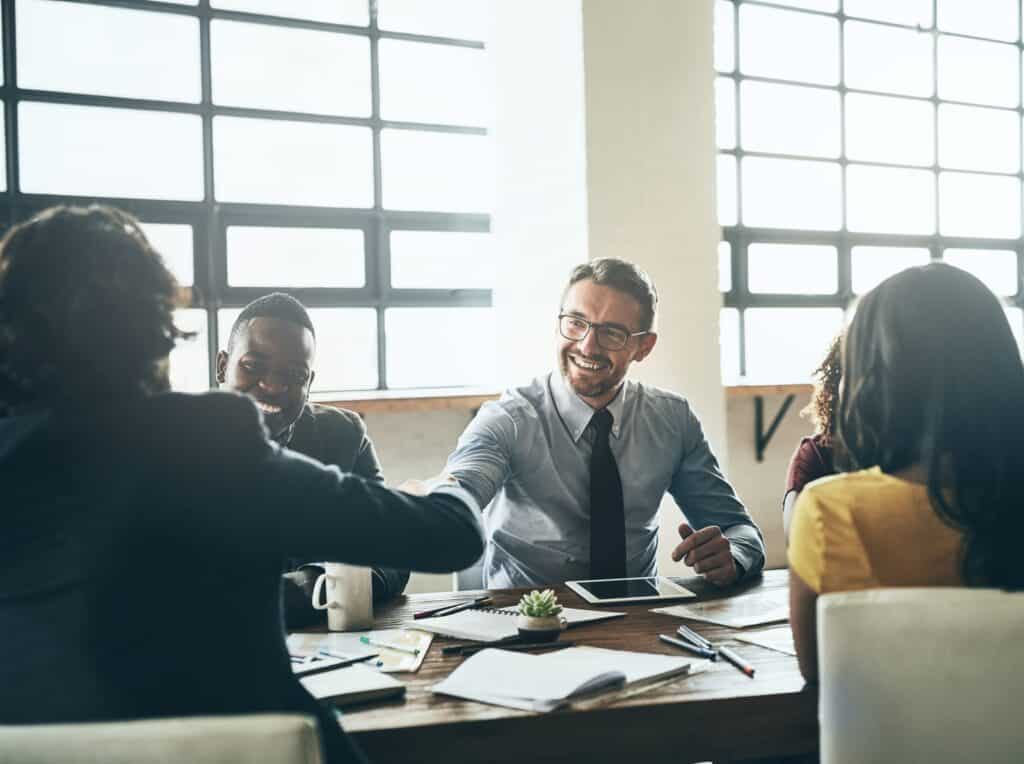 A group of business people shaking hands at a meeting.